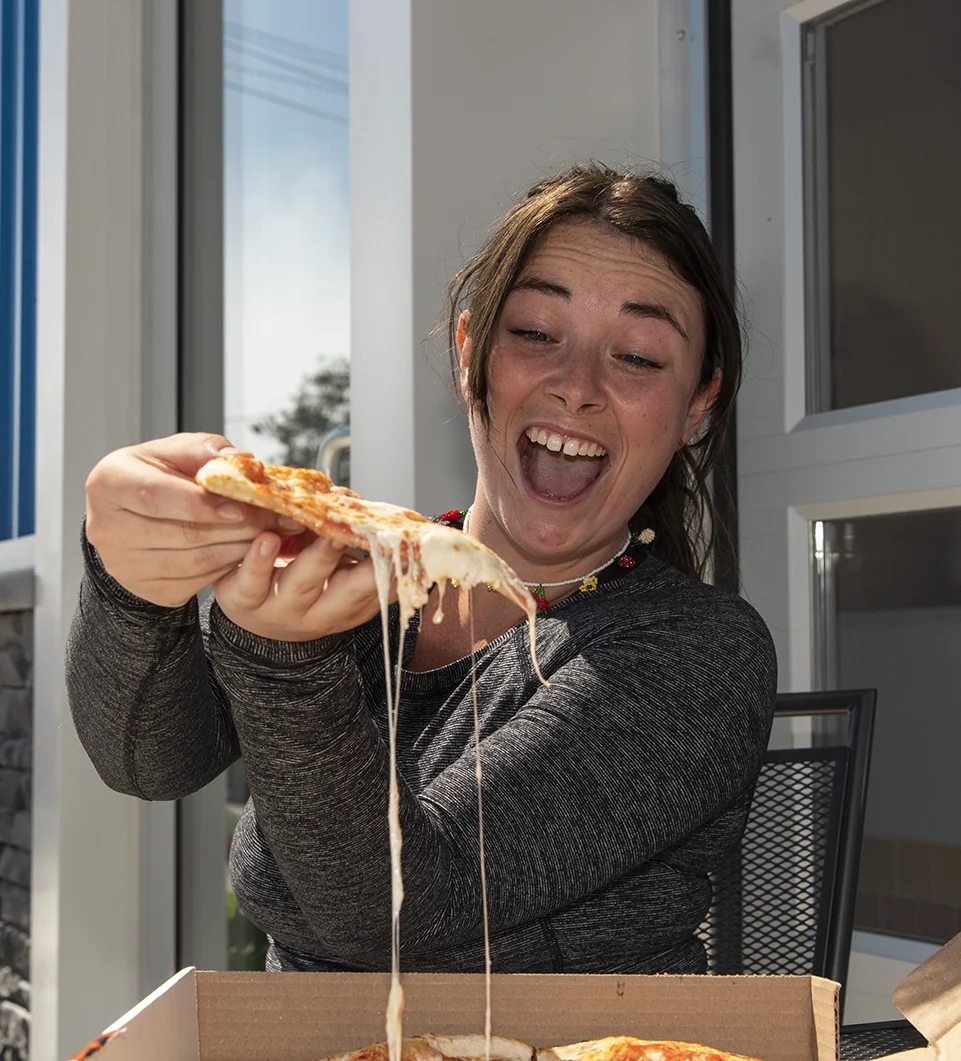 A lady grabbing a slice of pizza