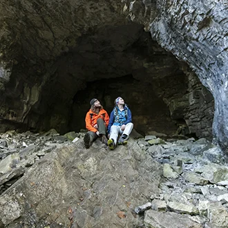 Two individuals sitting in a cave looking at the structure